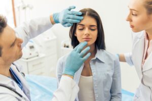 Woman sitting in a doctor's office with her face being examined